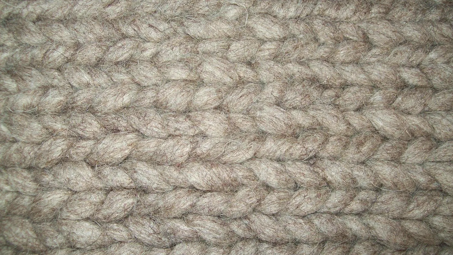 Primer plano del tejido grueso de una chomba de lana color beige